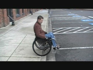 manual wheelchair using using a wheelie to propel down a curb.